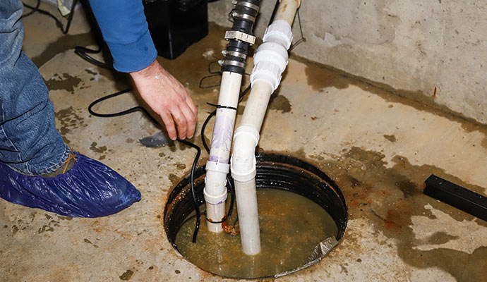 Plumber repairing sump pump in the flooded basement